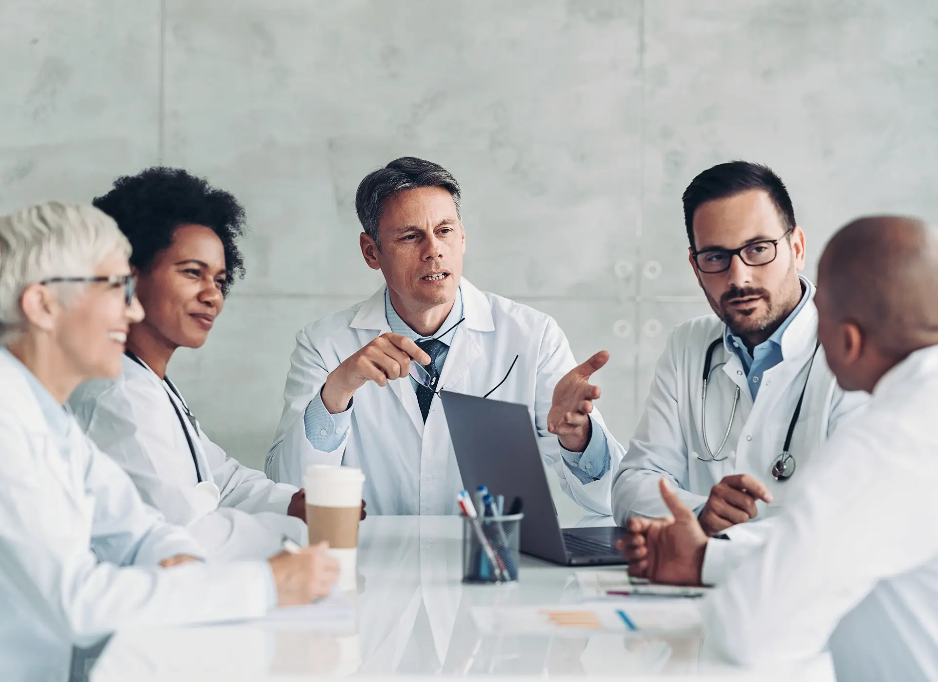 Three doctors having a discussion around a table in a medical setting.